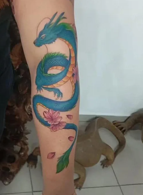 Tatuagem colorida de dragão oriental com flores de cerejeira no antebraço