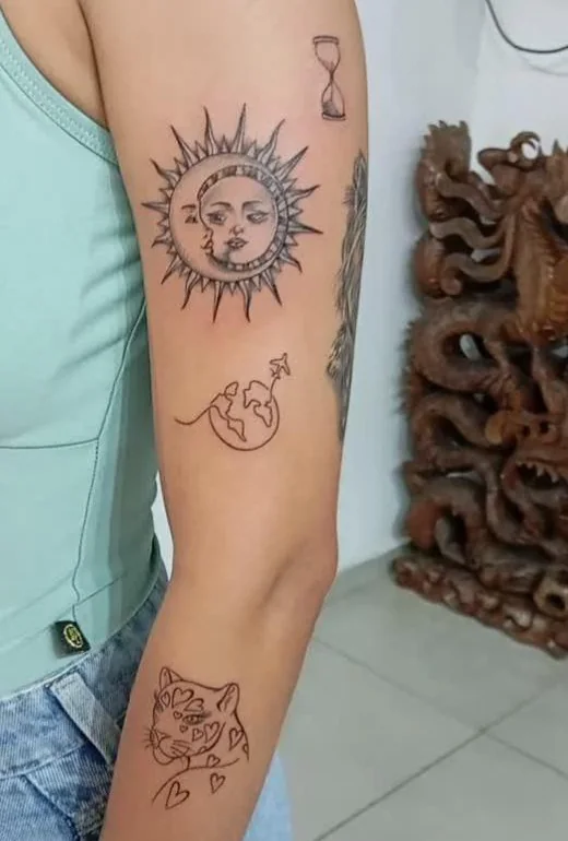 Tatuagens fineline de sol e lua, mundo e onça no braço